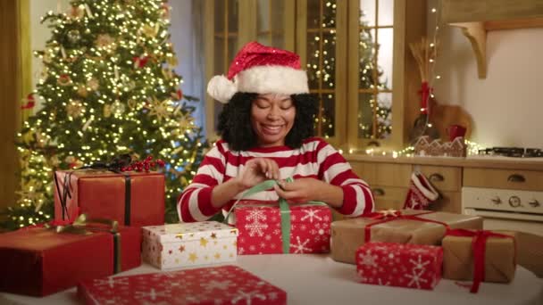 Усміхнена Африканська Леді Різдвяному Вбранні Готує Різдвяні Подарунки Сидячи Штаті — стокове відео