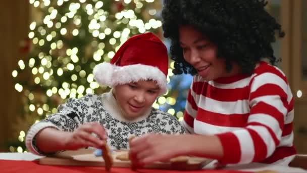 卷曲的黑发母亲与混血儿一起在装饰华丽的厨房里度过时光 装饰着明亮的圣诞树 玩自制饼干 高质量的4K镜头 — 图库视频影像