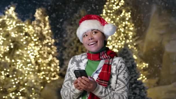 穿着羊毛衫 面色红润 面色苍白的女士站在室外手机上留言 冬天的童话 有着明亮的针叶树 高质量的4K镜头 — 图库视频影像