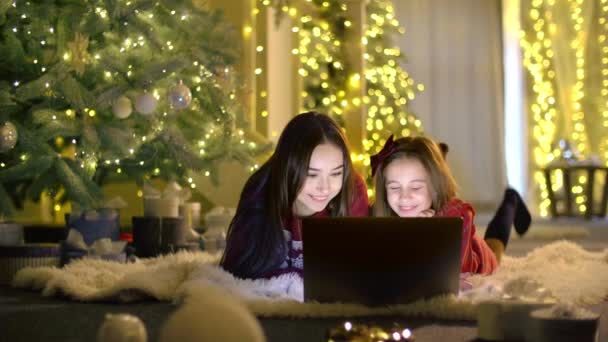 Zusters Kijken Leuke Series Met Kerstboom Achtergrond Meisjes Genieten Van — Stockvideo
