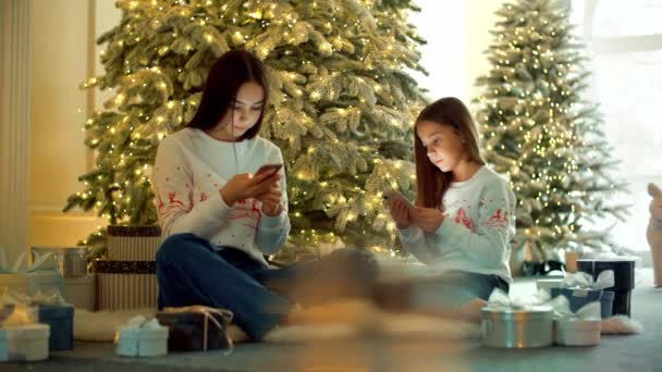 Dziewczyny Używają Komórek Salonie Pełnym Świątecznych Dekoracji Siostry Piszą Przyjaciół — Wideo stockowe