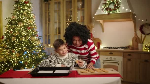 圣诞精神在装饰华丽的厨房里 妈妈和小儿子吃着刚烤好的姜饼饼干 围坐在餐桌旁 点缀着糕点 高质量的4K镜头 — 图库视频影像