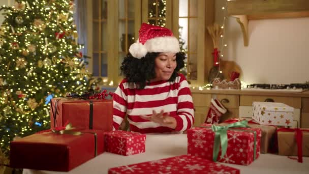 兴奋迷人的深色皮肤女性坐在装饰华丽的现代厨房里 点亮圣诞树 选择盒子 打开礼物 高质量的4K镜头 — 图库视频影像