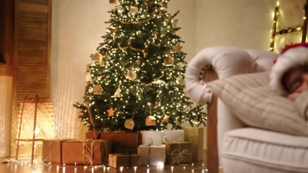 Prachtige Verlichte Kerstboom Met Geschenkdozen Eronder Kind Van Jaar Kerstmuts — Stockvideo