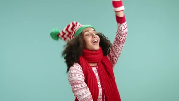 冬の装飾とセーターで遊び心のあるカーリーな若い女性は笑顔 ダンス 手を上げて下げ 横から緑の背景に頭を移動します 高品質の4K映像 — ストック動画