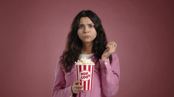 긴장한 소녀는 영화를보고 팝콘에 문질러 그녀는 분홍색 배경에 복장에 고품질 — 비디오