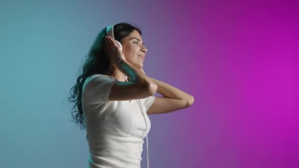 这个女孩带着耳机随着音乐跳舞 她双手紧紧抓住耳机 跟着音乐的节奏走 高质量的4K镜头 — 图库视频影像