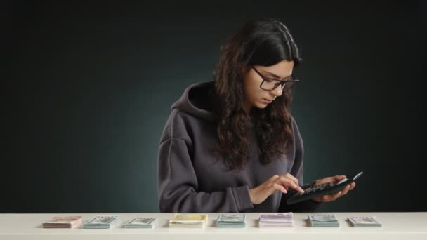 Μια Γυναίκα Γυαλιά Υπολογίζει Προσεκτικά Χρήματα Μια Αριθμομηχανή Τακτοποιημένα Στοιβαγμένα — Αρχείο Βίντεο