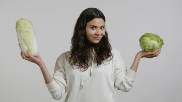 Μια Νεαρή Γυναίκα Δείχνει Δύο Διαφορετικά Λάχανα Φοράει Λευκή Κουκούλα — Αρχείο Βίντεο