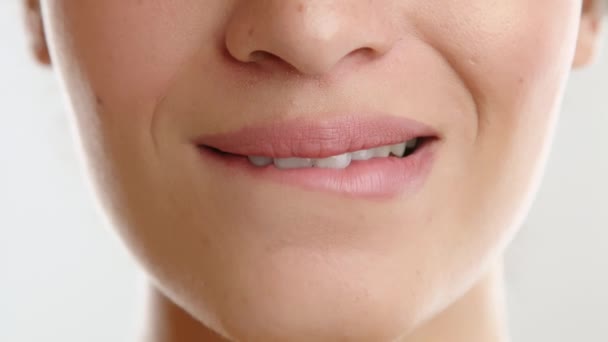 自然な色の口紅が付いている若い女性の美しい完全な唇 低い唇を魅惑的に噛む女性 暖かさを表現する表面の閉口の笑顔 高品質の4K映像 — ストック動画