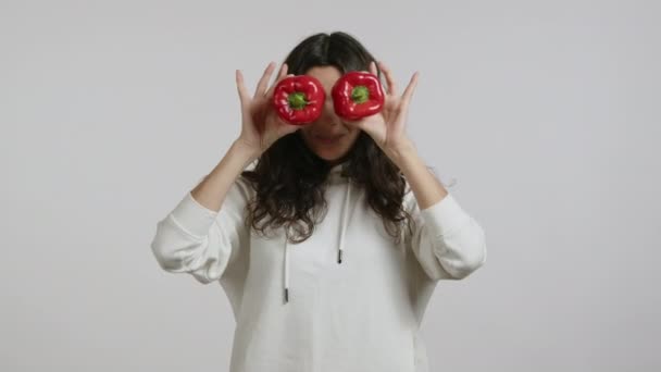 Ένα Όμορφο Κορίτσι Δείχνει Δύο Κόκκινες Πιπεριές Φοράει Λευκή Κουκούλα — Αρχείο Βίντεο