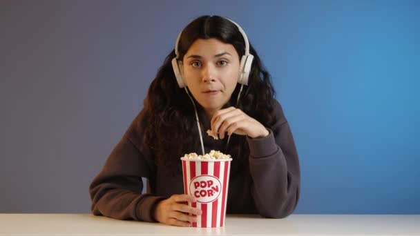 Młoda Brunetka Słuchawkach Patrzy Prosto Kamerę Bez Przerwy Popcorn Smutny — Wideo stockowe