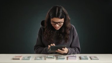 Bir kız hesap makinesine para sayıyor ve çok mutlu çünkü çok parası var. Duygularını dizginlemiyor. Yüksek kalite 4k görüntü