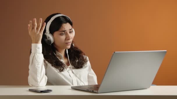 Dziewczyna Słuchawkami Siedzi Przy Laptopie Patrzy Coś Zasmuca Gestuje Rękami — Wideo stockowe
