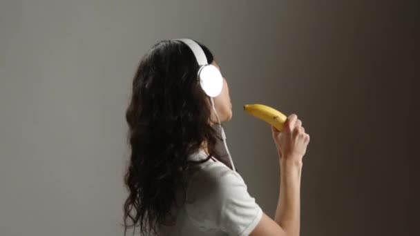 Szczęśliwa Dziewczyna Słuchawkach Tańczy Śpiewa Wymyślonego Mikrofonu Bananowego Jest Bardzo — Wideo stockowe