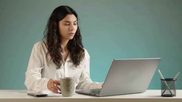 这个女孩正在她的笔记本电脑上平静地工作 一边喝着咖啡 一边继续工作 桌上有一台笔记本电脑 一部手机和铅笔 高质量的4K镜头 — 图库视频影像