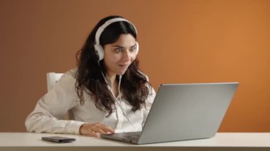 Beyaz kulaklıklı güzel bir kız dizüstü bilgisayarında bir video izliyor. Coşkuyla tezahürat yapıyor ve neşeli duygularını zapt edemiyor. Yüksek kalite 4k görüntü