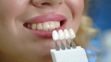 Dişçi muayenehanesinde tanınmayan genç bir kadın, yüksek kaliteli gözlük ve boylarda diş implantı seçiyor, diş implantı yaptırıyor. Yüksek kalite 4k görüntü