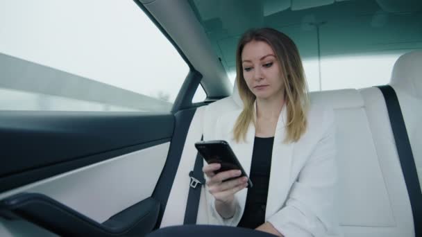 Piękna Blondynka Białej Kurtce Siedzi Tylnym Siedzeniu Samochodu Pracując Nad — Wideo stockowe