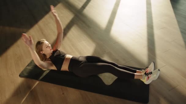 一个体格健壮的女孩在一间阳光充足的房间里躺在黑色的垫子上做着举重运动 高质量的4K镜头 — 图库视频影像