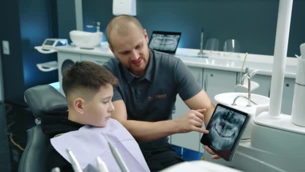 可供治疗的牙科专家咨询9 10岁男性患者 使用带Mri扫描牙齿的石碑 舒适的带有白色家具的牙医办公室 现代设备 高质量的4K镜头 — 图库视频影像