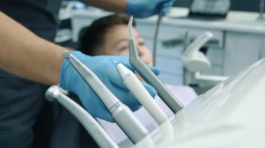 Tıbbi eldivenler konusunda uzman erkeklerin elleri 9-10 yıllık hastaların ağız boşluğunu temizlemek için özel boru ve su püskürten modern diş türbini kullanıyor. Yüksek kalite 4k görüntü