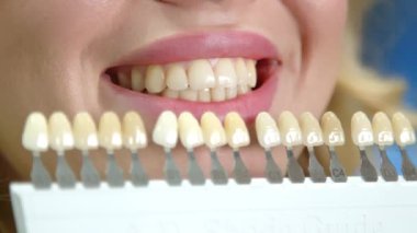 Dudakları dolgun genç bir kadın dişlerini gösteriyor, dişlerinde uygun implantı seçmekte zorlanıyor, en yüksek kalitede yapay diş örnekleri, diş bakımı. Yüksek kalite 4k görüntü