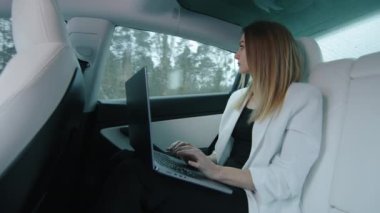 Beyaz saçlı, beyaz ceketli, beyaz koltuklarda oturan bir iş kadını laptopunda çalışıyor, iş meseleleriyle ilgileniyor. Yüksek kalite 4k görüntü