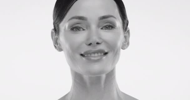 カメラで笑顔で完璧な肌と歯を持つ華やかな女性をフィーチャーした黒と白のビデオ 明るいバックグラウンドで非常に近いショット 高品質の4K映像 — ストック動画
