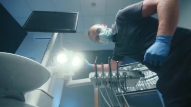 Kalkan maskeli bir erkek dişçi ve lateks eldivenli bir lambanın ışığını kameraya çeviren türbinden su fışkırtan hasta bakış açısı. Yüksek kalite 4k görüntü