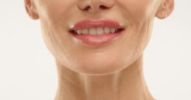 Kar beyazı dişleri olan ve cildine özen gösteren 50 yaşında bir kadın yüzü. O hafifçe gülümsüyor. Cilt bakımı. Sağlık ve güzellik. Yüksek kalite 4k görüntü.