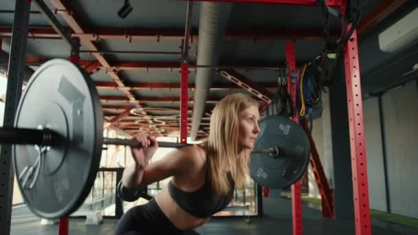 一位运动员背着杠铃在蹲着 她正在准备参加体育竞赛 这个女孩正在一家健身房为专业人员进行专业培训 高质量的4K镜头 — 图库视频影像