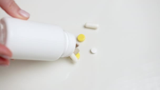 Eine Frauenhand Gießt Viele Verschiedene Tabletten Aus Einem Weißen Behälter — Stockvideo