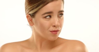 Stüdyodaki bir model kendini biraz huzursuz hisseder ve kendi suçluluğunu hissederek bakışlarını başka yöne çevirir. Yine de, yüzünde yavaşça nazik bir gülümseme beliriyor. Yüksek kalite 4k görüntü.