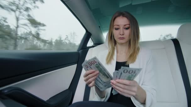 坐在后座上的一位女商人算上一百美元的钞票 她穿着正式的白色衣服 这个女人很细心 生意和钱高质量的4K镜头 — 图库视频影像