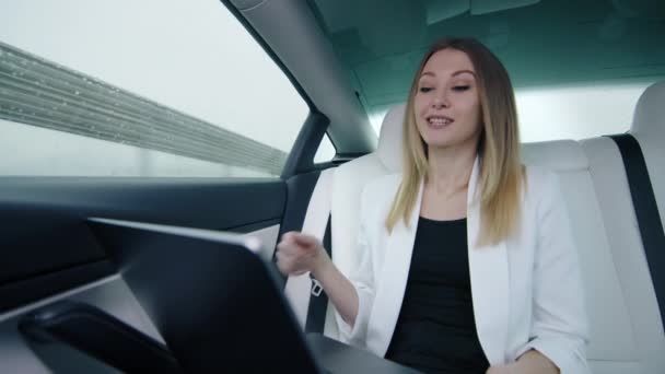 美しいビジネスウーマン ブロンドは ビジネスパートナーとオンラインビデオ通話を行い 重要な問題を解決します 彼女は動く車の中で満足して話す 高品質の4K映像 — ストック動画