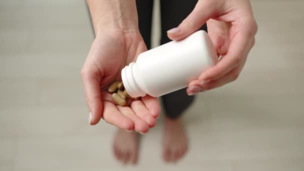 Uma Menina Está Derramando Pílulas Marrons Naturais Uma Caixa Branca — Vídeo de Stock