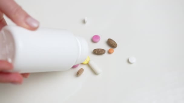 Kézzel Elegánsan Öntjük Színes Tabletták Keverékét Egy Üvegből Egy Fehér — Stock videók