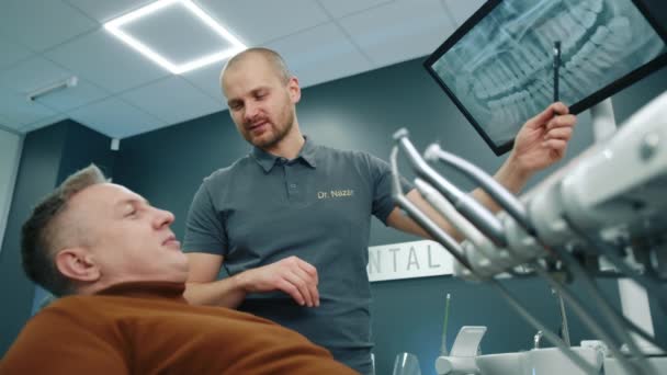 Улыбающийся Стоматолог Указывающий Экран Помощью Мрт Зубов Дающий Консультации Человеку — стоковое видео