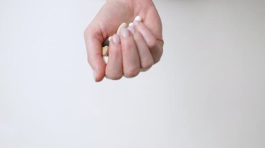 Çekimde sıkılmış bir yumruk, avuç içinin üzerinde duran çok çeşitli renkli hapları ortaya çıkararak, sağlık ve ilaç seçeneklerindeki hayati seçimi betimliyor..