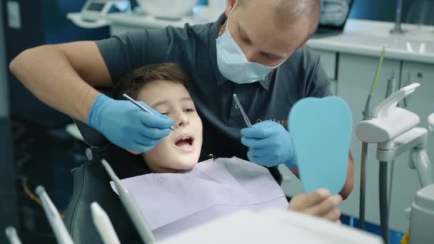Kalme Jongen Zit Tandartsstoel Openen Mond Wijd Terwijl Tandheelkundige Expert — Stockvideo