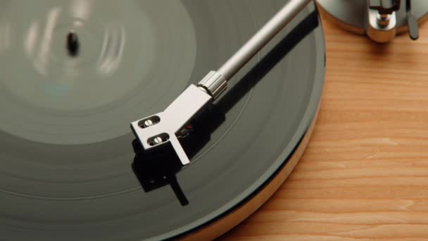 关闭一个乙烯唱机针微妙地触摸专辑表面 旋转盘上的凹槽捕捉了在木制背景下复古音频技术的本质 — 图库视频影像