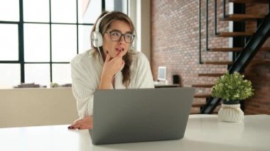 Uzaktan kumandalı iş. Keyfi yerinde bir kız şık dairesinde büyük güneşli pencereli bir bilgisayarda çalışıyor. Kulaklıkla müzik dinlemek. Kırmızı 8K RAW.