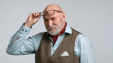 50 'li yaşlarda sofistike bir adam kadehini kaldırıyor, tek gözüyle göz kırpıyor, oyuncu ama zarif bir tavır sergiliyor. Tüvit bir yelek giymişti, açık gri bir arka planda cazibe yayıyordu. Kırmızı 8K RAW