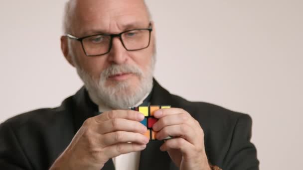 사업가는 집중적으로 다채로운 큐브를 해결하려고합니다 자신의 지위를 강조하는 넥타이와 턱시도에있다 — 비디오