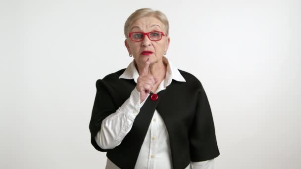 严格整洁的老妇人 戴着红色口红 戴着红边眼镜 穿着白衬衫 黑色夹克 要求保持安静 挥动食指 高质量的4K镜头 — 图库视频影像