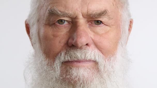 一个留着灰白胡子的老人的特写镜头 他严肃地看着摄像机 他的目光很严肃 情绪很压抑 祖父的背景是白色的 红色8K红色 — 图库视频影像