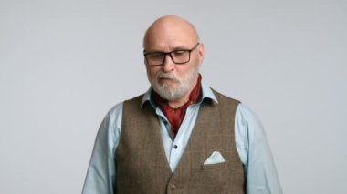 Orta yaşlı bir adam beceriksizce bakıyor, yüz ifadelerinden ne gördüğüne dair bir anlayış eksikliği gösteriyor. Gözlüklü ve atkısı olan klasik bir yelek giyen adam. Kamera 8K HAM.