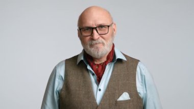 Şık giyinmiş orta yaşlı bir adam gergin bir şekilde dudağını ısırıyor ve bir anlık endişeyi yakalıyor. Onun keskin görünüşü tüvit bir yelek ve açık mavi gömlekle vurgulanır. 8K HAM.