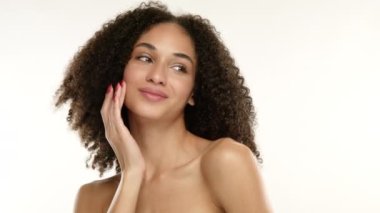 Afro saç stili kahverengi bukleli genç bir kadının portresi, doğal makyajlı pürüzsüz bir cilt, cilt rahatsızlığı, vücuda dokunmak, yüze dokunmak. Yüksek kalite 4k görüntü